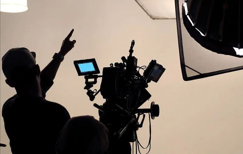 Siluett av en kameraman som pekar under en filmproduktion i en studio.